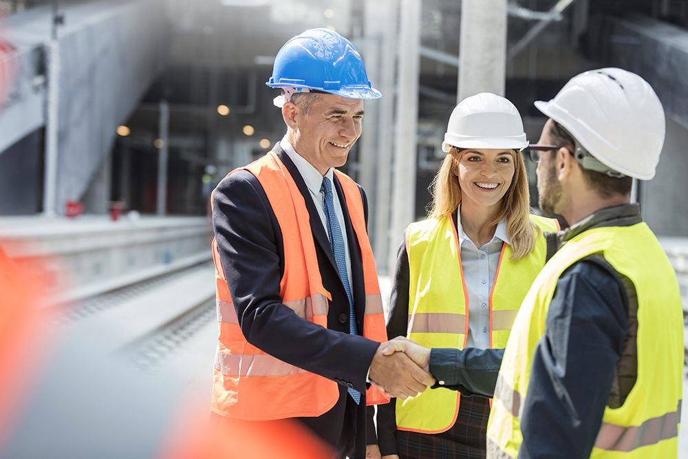 Executive shaking construction workers hand at construction site.